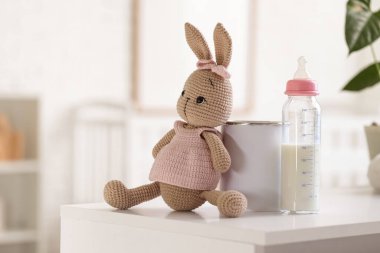 Şişe süt formülü ve oyuncak tavşan yatak odasında klozette, yakın plan.