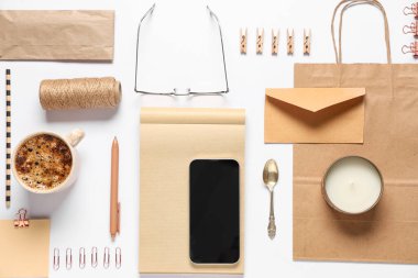 Beyaz arkaplanda cep telefonu, ambalaj ögeleri ve dağıtım kağıt torbasıyla kompozisyon