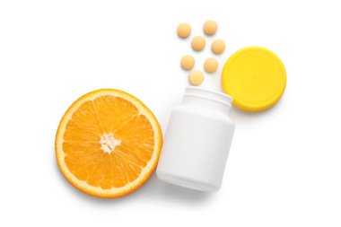 C vitamini hapları ve beyaz arka planda portakal dilimi olan şişe.