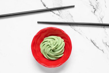 Beyaz arka planda wasabi macunu ve çubuk ile kase