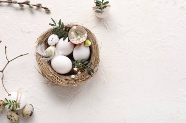 Nest with Easter eggs, leaves, gypsophila flowers and pussy willow branch on white background