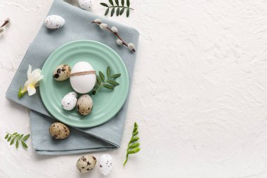 Plate with Easter eggs, leaves, beautiful flower and pussy willow branch on white background
