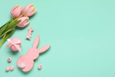 Paskalya yumurtaları, dekoratif tavşanlar ve turkuaz arka planda lale çiçekleri olan kompozisyon