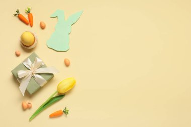 Paskalya yumurtaları, hediye kutusu ve bej arka planda lale çiçeği olan kompozisyon