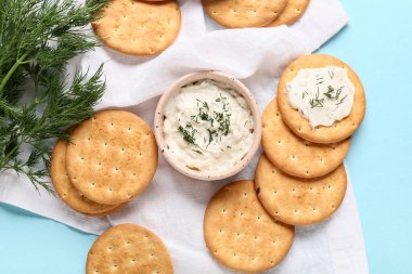 Lezzetli krakerler, mavi arka planda dereotu ve bir kase sos, yakın plan.