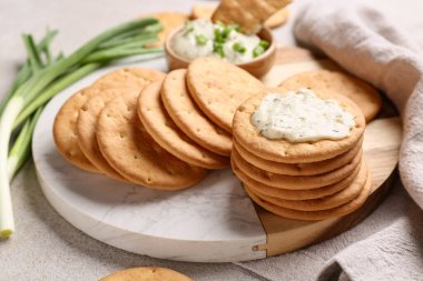 Lezzetli krakerler, yeşil soğan ve soslu beyaz grunge arka planı, yakın plan.