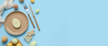 Tatlı kurabiyeli güzel masa, Paskalya yumurtaları ve açık mavi arkaplanda açık mavi arkaplanlı ahşap tavşancık.