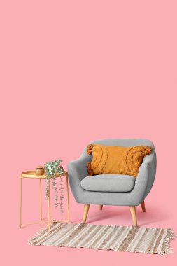 Masalı gri koltuk ve pembe arka planda halı.