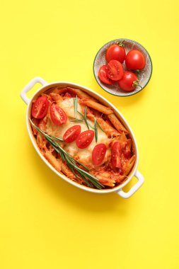 Sarı arka planda domates soslu ve peynirli makarna kabı.
