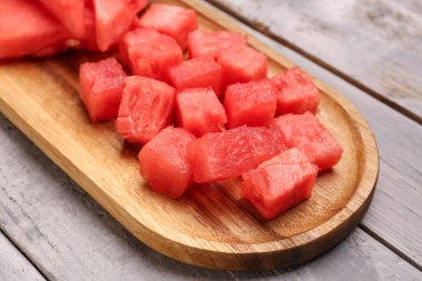 Gri ahşap arka planda taze karpuz parçaları olan tahta.