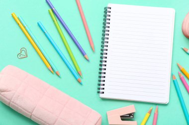 Turkuaz arka planda kırtasiye malzemesi olan bir sürü renkli kalem