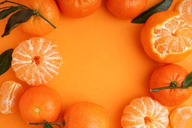 Frame made of tasty tangerines with leaves on orange background