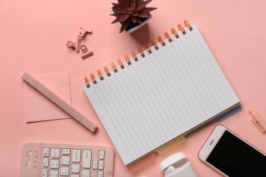 Pembe arka planda defter, klavye ve telefon ile kompozisyon. Üst görünüm