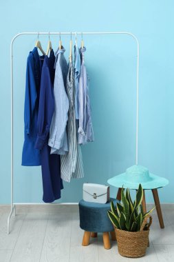 Mavi duvarın yanında kadın kıyafetleriyle dizilin.