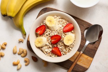 Tahta tepsi, fındık, çiğ yulaf ezmeli kase, arka planda muz ve böğürtlen, yakın plan.