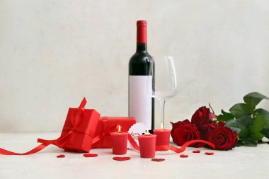 Mum dolu hediye kutuları, bir şişe şarap, cam ve gül çiçekleri açık arkaplanda Sevgililer Günü kutlaması için.