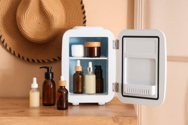 Odadaki bej duvarın yanındaki çekmecelerde kozmetik ürünleri olan küçük bir buzdolabı. Yakın çekim.