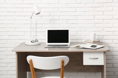 Bilgisayarı beyaz tuğla duvarın yanında olan modern ofis.