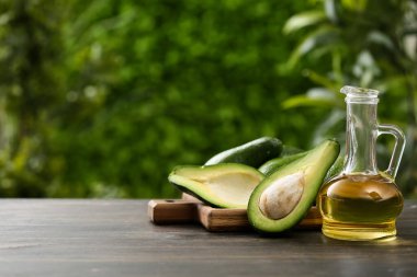 Bir sürahi taze yağ ve açık havada ahşap masa üzerinde avokado kesme tahtası.