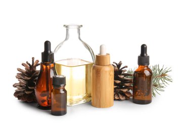 Beyaz zemin üzerinde çam kozalakları ve köknar dalı olan gerekli yağ şişeleri