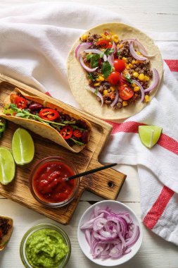 Lezzetli taze taco tepsisi ve ahşap arka planda malzemeler.