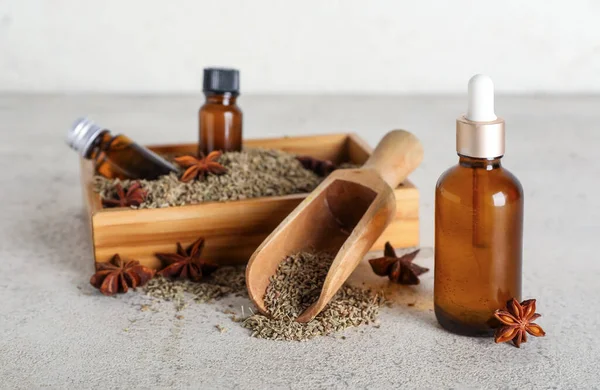 Ahşap tepside gerekli yağ şişeleri, anason yıldızları, kurutulmuş tohumlar ve gri grunge masasında kepçe