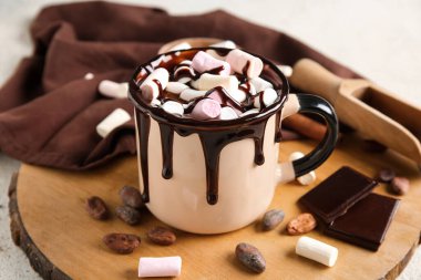 Bir fincan kremalı sıcak çikolata ve arka planda kakao çekirdeği.