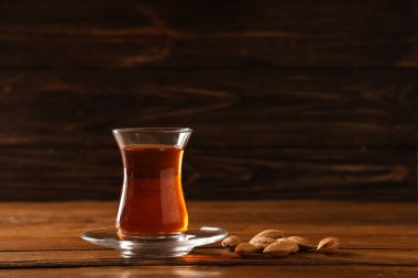 Tahta zemin üzerinde badem olan bir bardak Türk çayı.