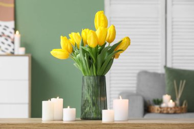 Güzel mumlar ve vazodaki lale çiçekleri odadaki masada, yakın plan.