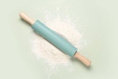 Açık yeşil arkaplanda yuvarlanan iğne ve un