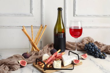 Lezzetli Grissini, jamon dilimleri, incir ve mermer masada bir bardak şarap.