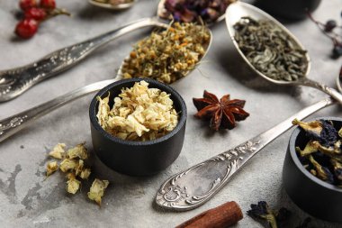 Gri grunge arka planda farklı kuru çay kaşıklarıyla kompozisyon, yakın plan