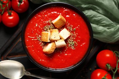 Bir kase lezzetli domates çorbası ve siyah grunge arka planda kızarmış ekmek, yakın plan.