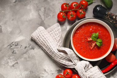 Bir kase lezzetli domates çorbası ve beyaz grunge arka planda malzemeler.