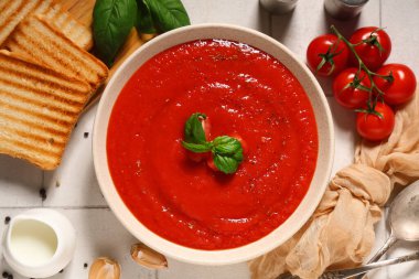 Bir kase lezzetli domates çorbası ve beyaz fayanslı malzemeler, yakın plan.