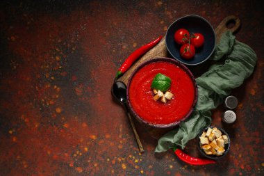 Bir kase lezzetli domates çorbası ve kahverengi grunge arkaplanda malzemeler.