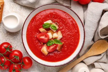 Bir kase lezzetli domates çorbası ve beyaz grunge arka planda malzemeler, yakın plan.