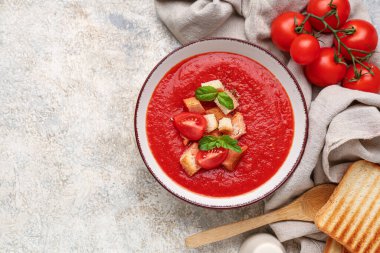 Bir kase lezzetli domates çorbası ve beyaz grunge arka planda malzemeler, yakın plan.