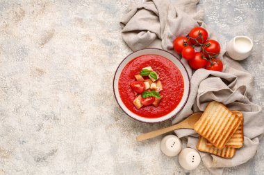 Bir kase lezzetli domates çorbası ve beyaz grunge arka planda malzemeler.