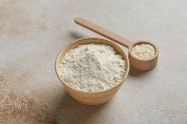 Bir kase süt tozu ve arka planda ahşap bir kepçe.