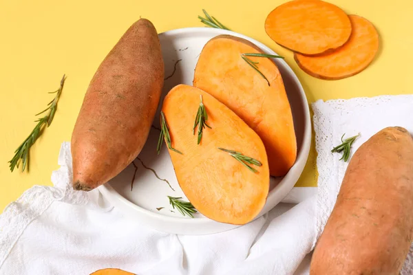 Sarı zemin üzerinde taze patates, tabak ve biberiye dalları olan kompozisyon