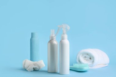 Mavi arka planda saç spreyi ve fırça şişeleri