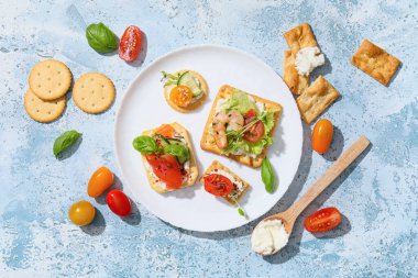 Farklı lezzetli krakerler, peynir, somon, karides ve baharatlar mavi grunge arka planda.
