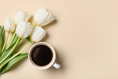 Bir buket lale çiçeği ve bej arka planda bir fincan kahve ile güzel bir kompozisyon.