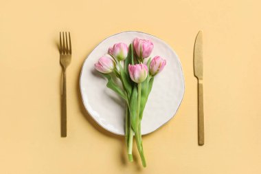 Sarı arka planda bir buket lale çiçeğiyle güzel bir masa.