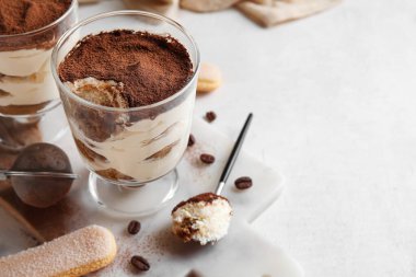Tatlı tiramisulu bardaklar, beyaz arka planda kurabiye ve kahve çekirdekleri