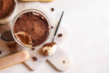 Tatlı tiramisulu bardaklar, beyaz arka planda kurabiye ve kahve çekirdekleri