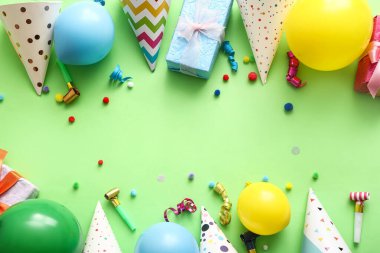 Yeşil arka planda parti şapkaları, düdükler, balonlar ve hediye kutusundan yapılmış çerçeve