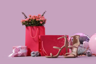 Disko topu, hediye paketleri ve arka planda balonlar olan şık topuklu ayakkabılar.