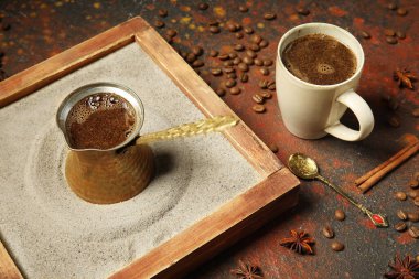 Kırmızı grunge arka planında farklı baharatlarla kumda bir fincan sıcak Türk kahvesi.
